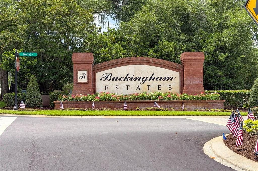 A brick monument sign for Buckingham Estates stands at a road intersection with American flags — 6230 BORDEAUX CIRCLE, SANFORD, FL