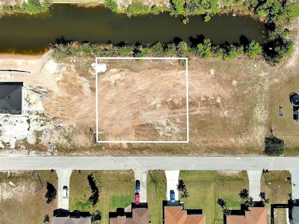 An aerial view shows a cleared, rectangular residential lot bordered by a road and canal — 1611 NW 2ND STREET, CAPE CORAL, FL