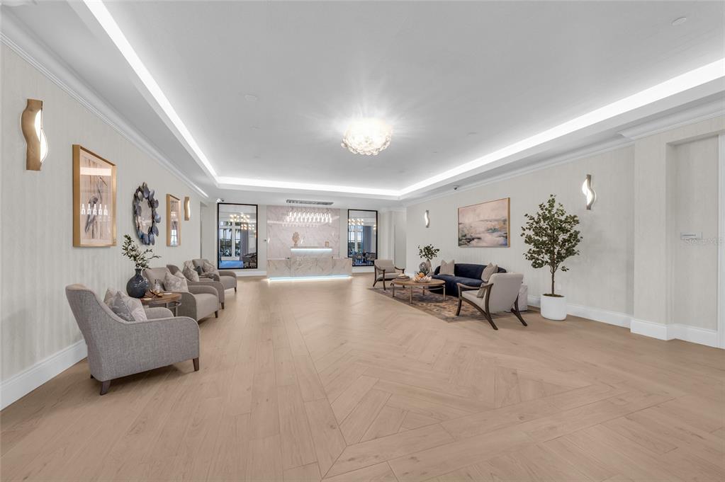 A spacious, modern lobby features light wood herringbone flooring, recessed lighting, and a marble reception desk — 6614 GRAND ESTUARY TRAIL UNIT 102, BRADENTON, FL