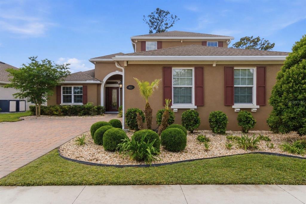 A two-story house with a brown stucco exterior, red shutters, and a landscaped front yard — 1022 VICTORIA HILLS DRIVE S, DELAND, FL