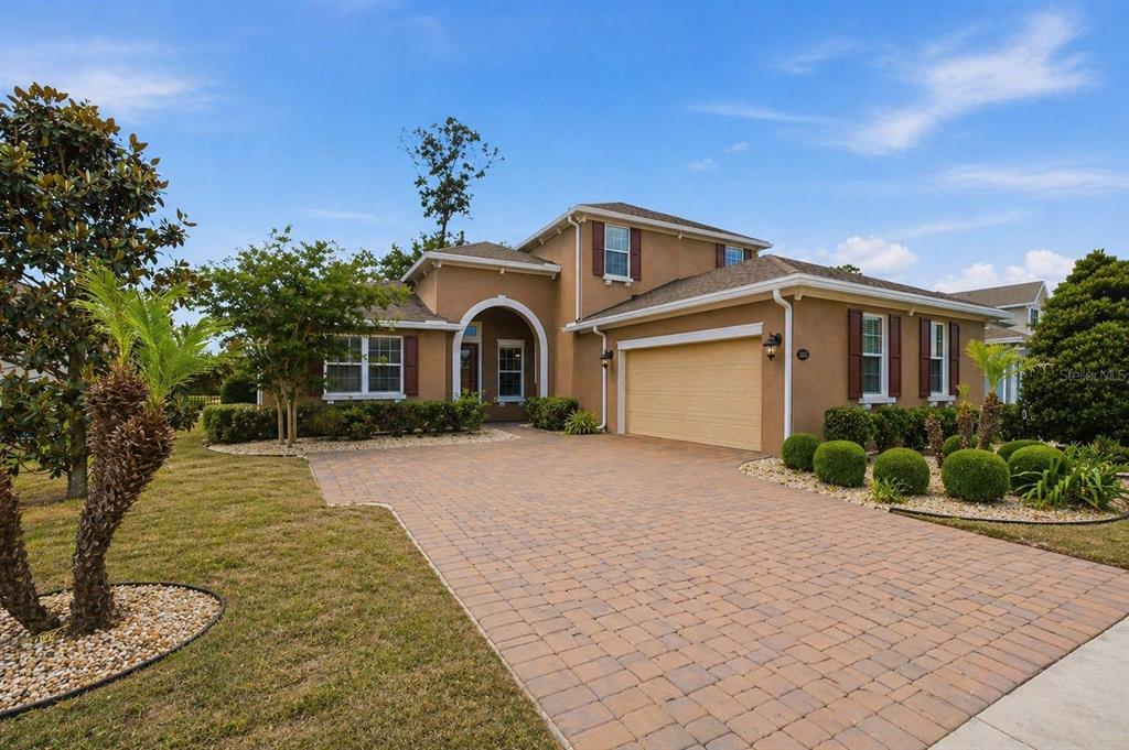 A two-story house with a tan stucco exterior, a paved driveway, and a two-car garage — 1022 VICTORIA HILLS DRIVE S, DELAND, FL