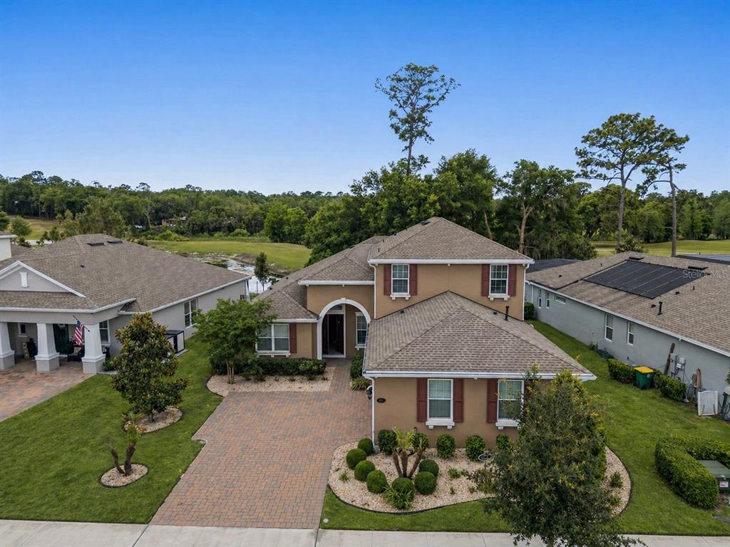 An aerial view of a two-story tan house with a brick driveway and landscaped yard — 1022 VICTORIA HILLS DRIVE S, DELAND, FL