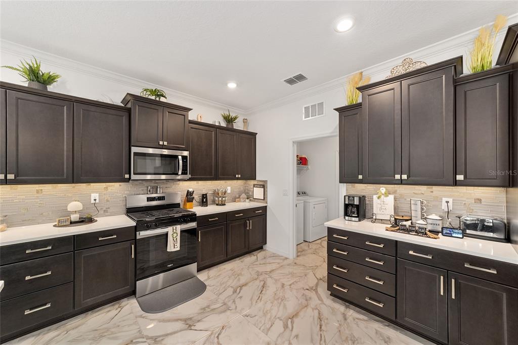 A kitchen features dark wood cabinets, white countertops, a tiled backsplash, and light marble flooring — 7037 SW 86TH AVENUE, OCALA, FL