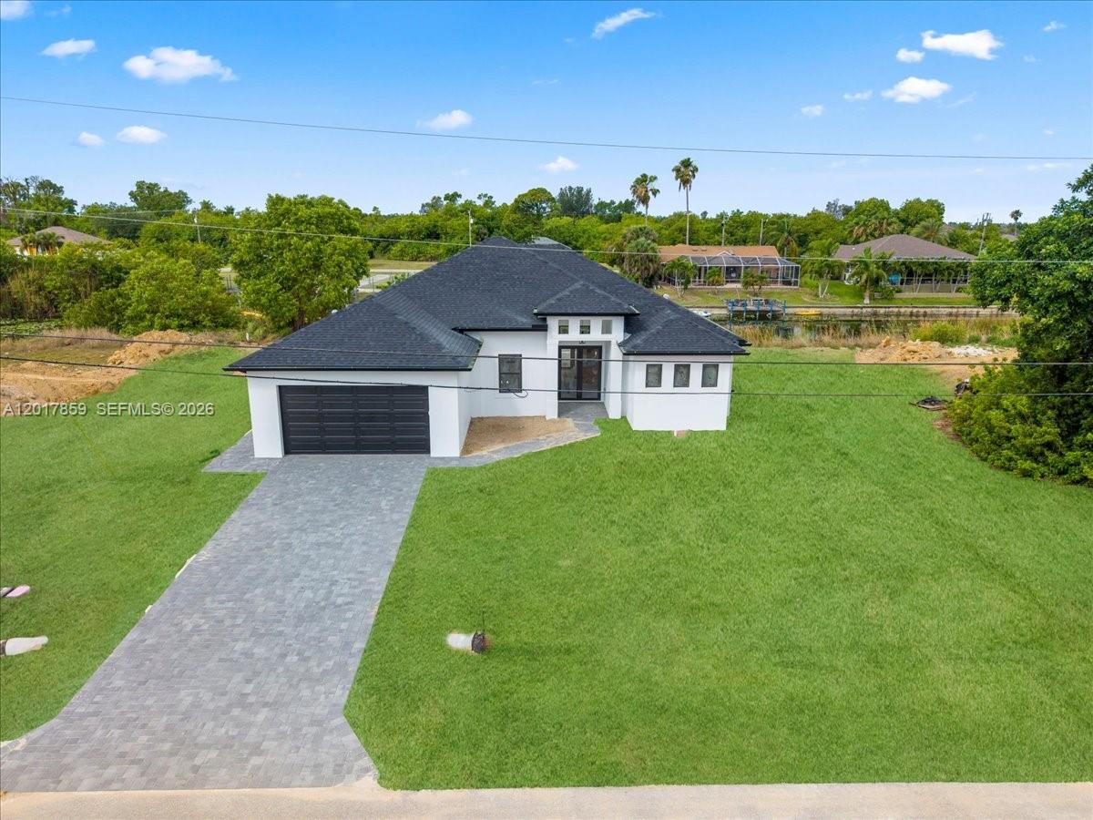 An aerial view shows a modern white house with a black roof and garage — 502 NE 5th PL, Cape Coral FL 33909, CAPE CORAL, FL