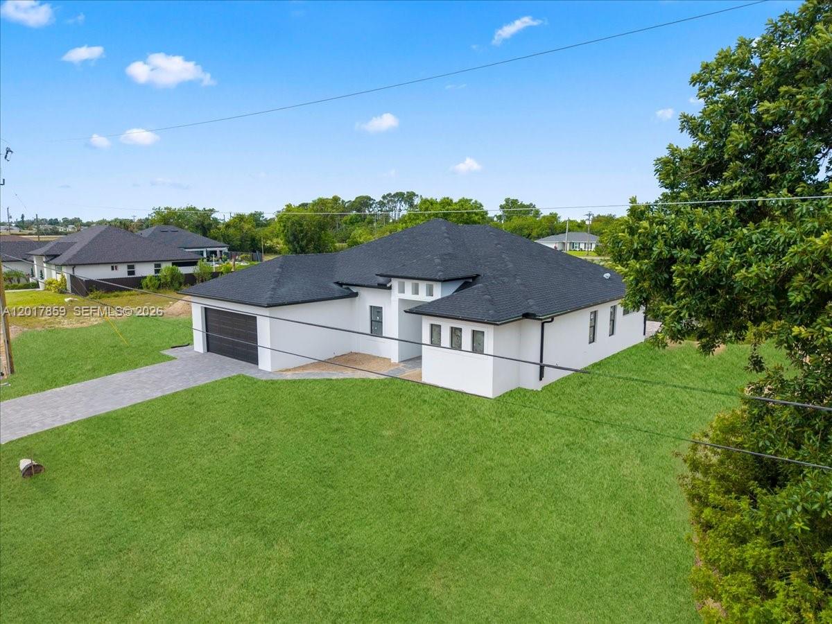 An aerial view of a modern, white single-story house with a dark shingled roof — 502 NE 5th PL, Cape Coral FL 33909, CAPE CORAL, FL