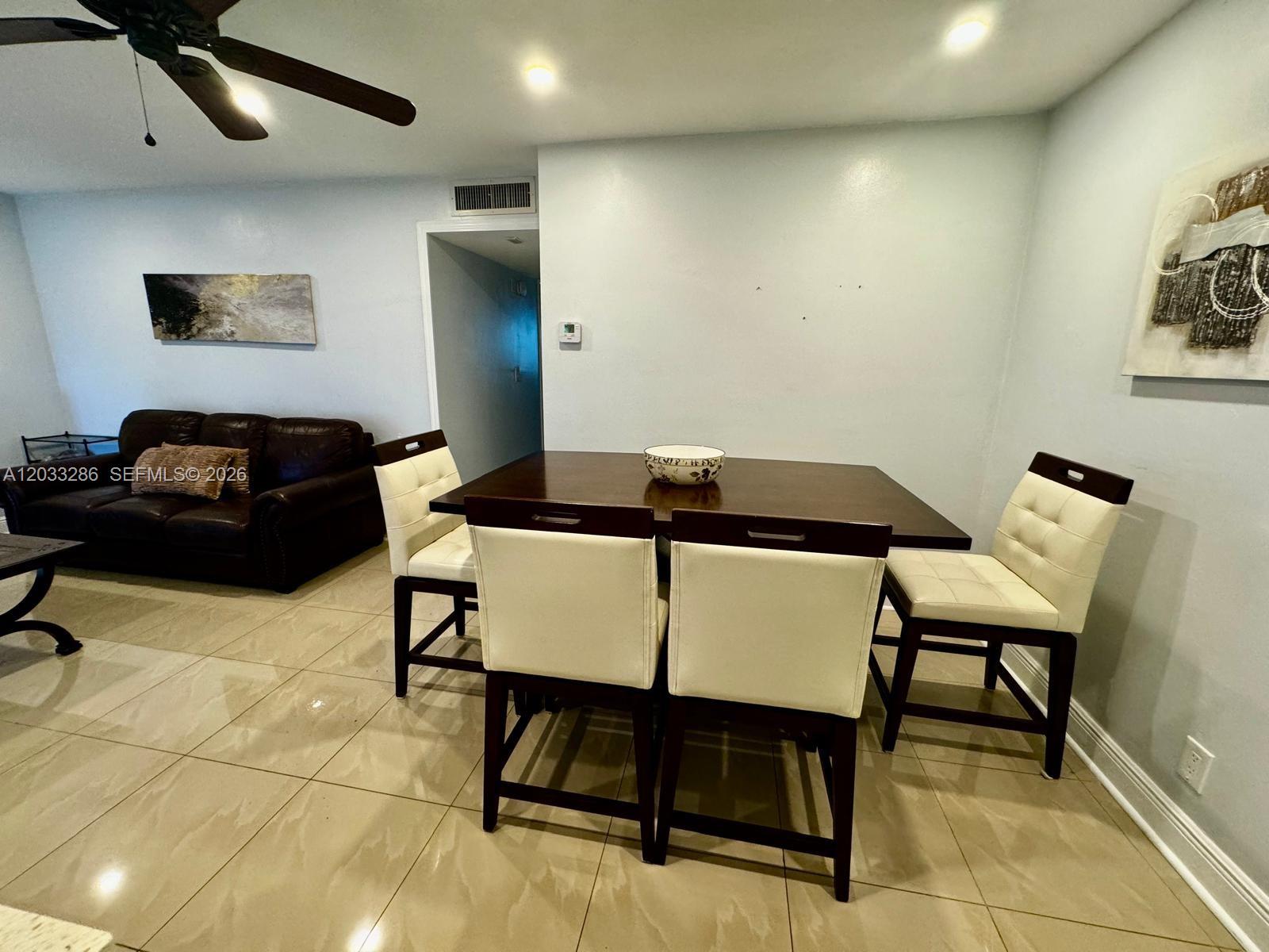 A dining area with a dark wood table and four cream-colored chairs on tiled floors — 5300 Washington St # H236, Hollywood FL 33021, HOLLYWOOD, FL