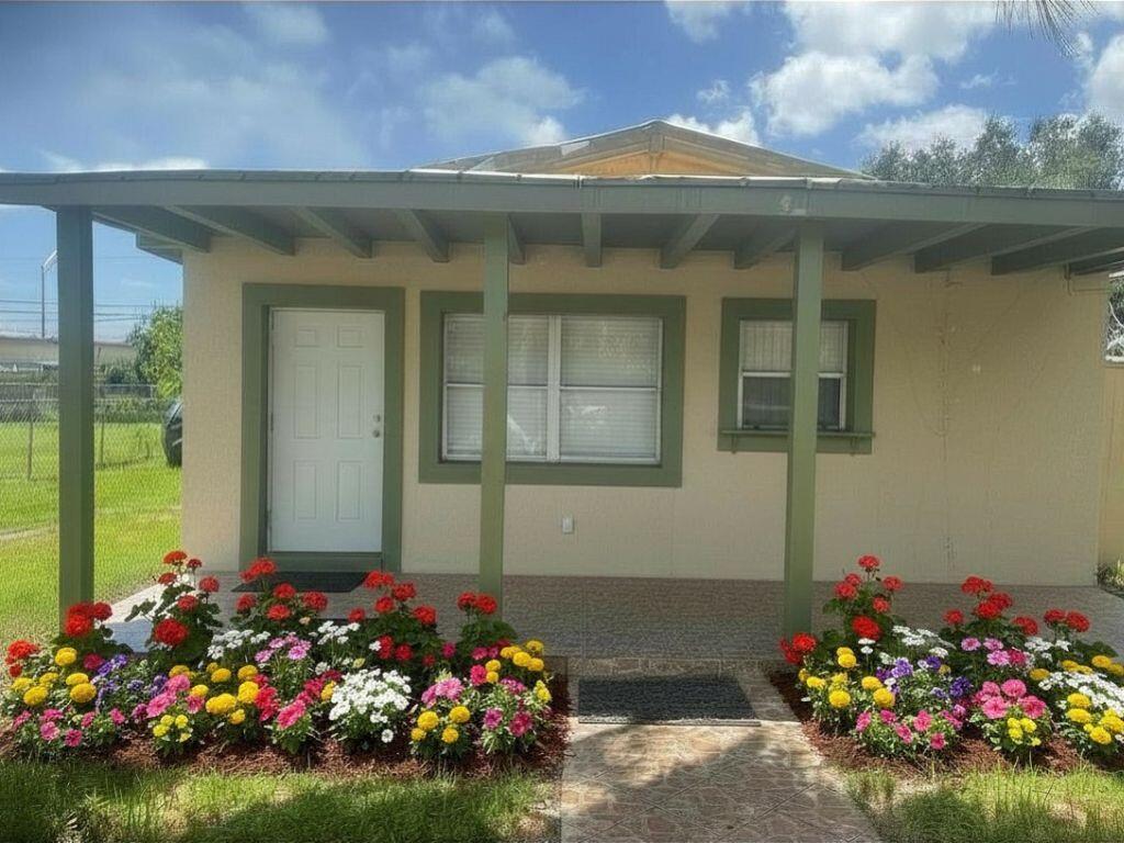 A single-story house exterior with a covered porch, green trim, and colorful flower beds — 4100 SW 28th Street, West Park FL 33023, WEST PARK, FL