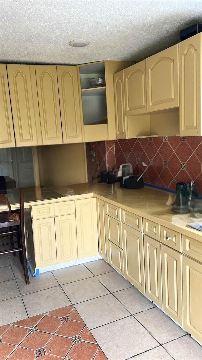 A kitchen features yellow cabinets, a red tiled backsplash, and light-colored floor tiles — 4100 SW 28th Street, West Park FL 33023, WEST PARK, FL