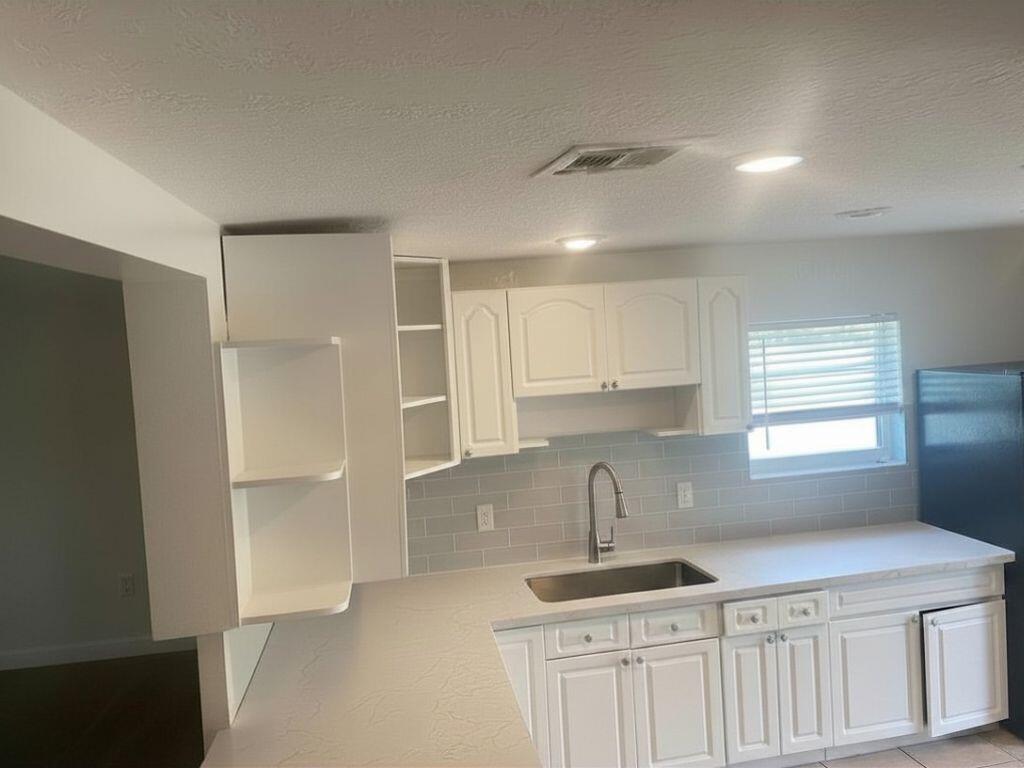 A kitchen features white cabinets, a stainless steel sink, and light gray subway tile backsplash — 4100 SW 28th Street, West Park FL 33023, WEST PARK, FL