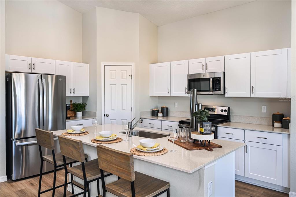 A kitchen features white cabinets, stainless steel appliances, and a central island with bar seating — 2330 STILLVIEW PASS, ZEPHYRHILLS, FL