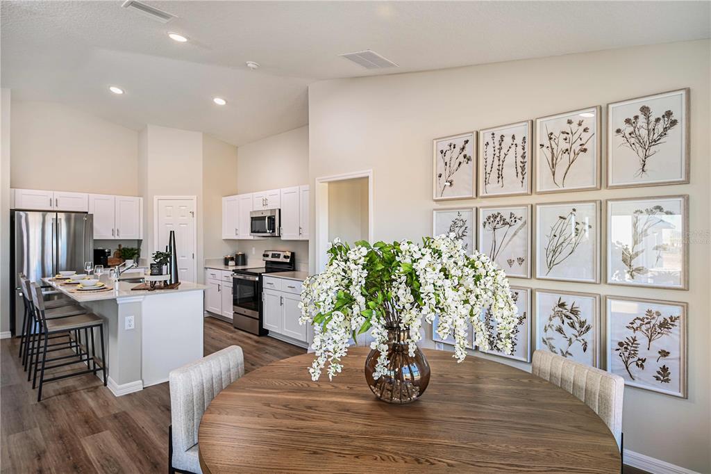 A kitchen with white cabinets and a dining area featuring a round wooden table — 2330 STILLVIEW PASS, ZEPHYRHILLS, FL