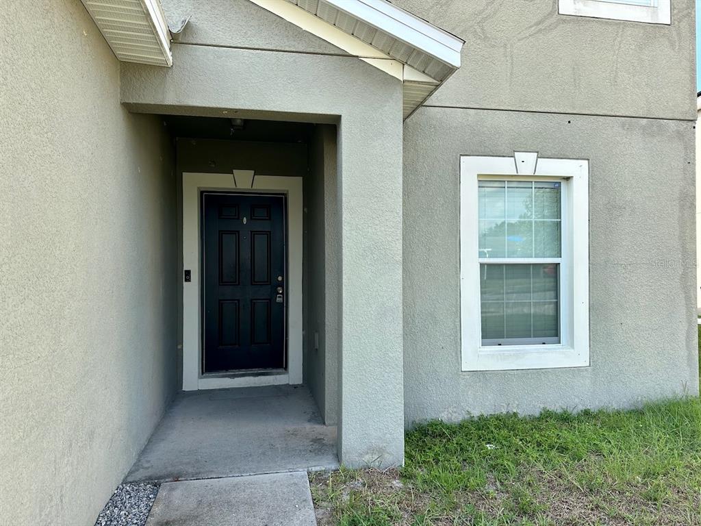 A front entryway with a dark door and a single window on a stucco exterior — 235 HIBISCUS STREET, WINTER HAVEN, FL