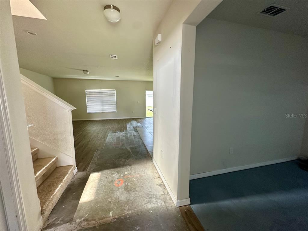 An interior view shows a staircase, a transition area with exposed subflooring, and a living space — 235 HIBISCUS STREET, WINTER HAVEN, FL