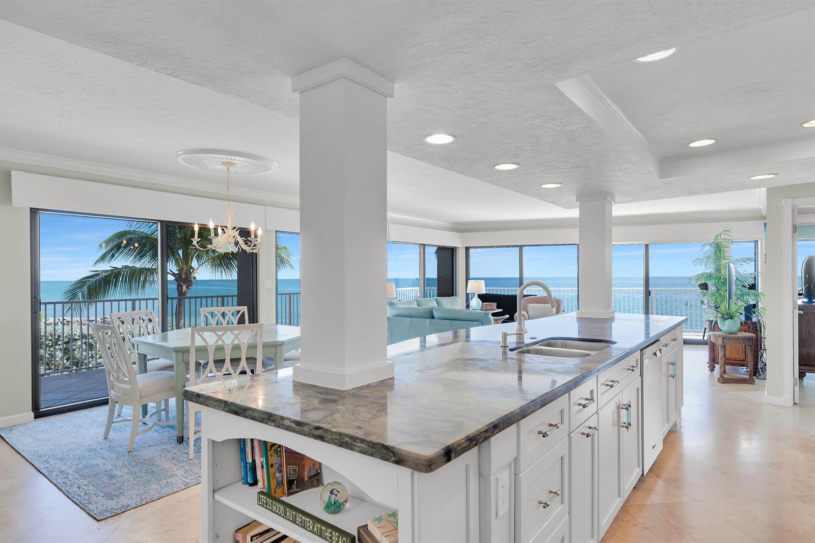 A kitchen island with a stone countertop overlooks a dining area and ocean views — 1133 W Ocean Drive # 17, FL 33050, FL