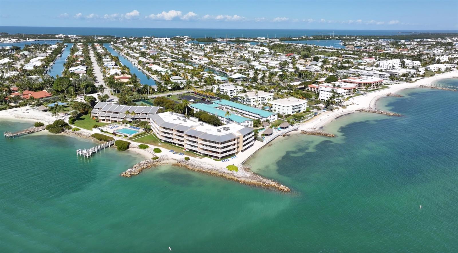 An aerial view shows a multi-story beachfront condominium complex surrounded by water and residential neighborhoods — 1133 W Ocean Drive # 17, FL 33050, FL