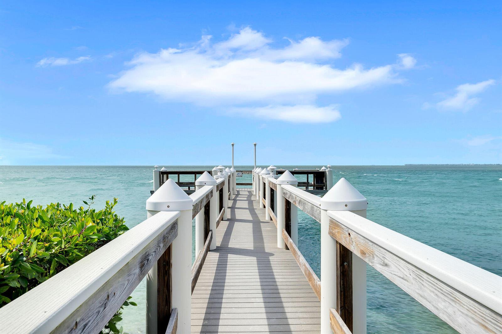 A wooden pier with white railings extends over turquoise water under a blue sky — 1133 W Ocean Drive # 17, FL 33050, FL