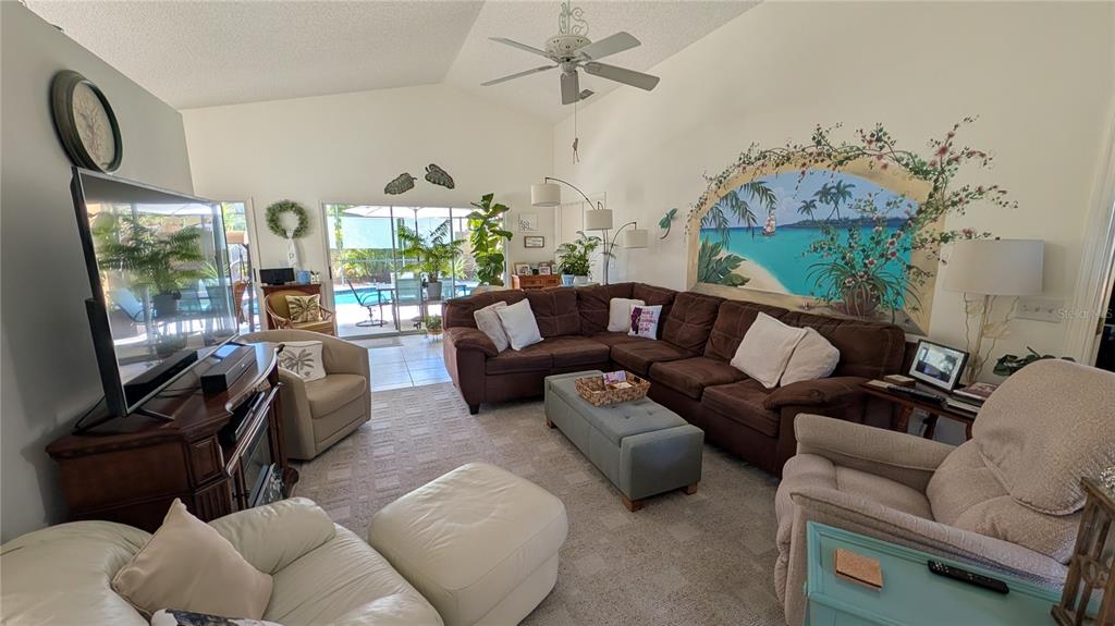 A living room features a large brown sectional, a mural, and sliding glass doors — 5406 83RD TERRACE E, SARASOTA, FL