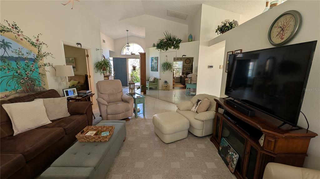 A living room features a brown sofa, a beige armchair with ottoman, and a television — 5406 83RD TERRACE E, SARASOTA, FL