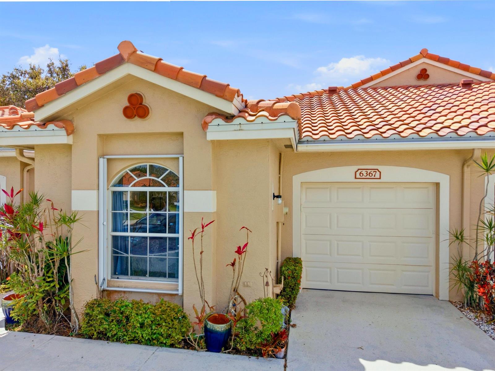 The exterior of a tan house features a tiled roof, a garage, and a front window — 6367 Long Key Lane, Boynton Beach FL 33472, BOYNTON BEACH, FL