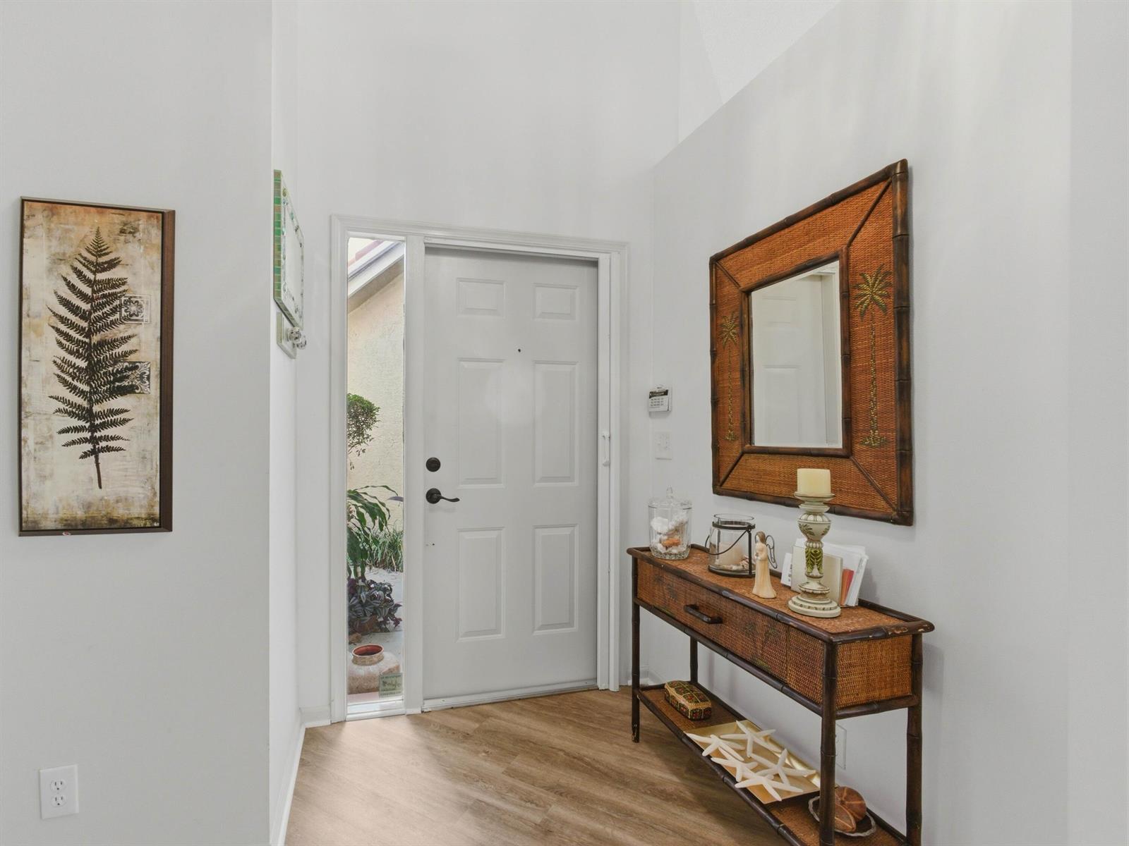 An entryway features a white front door, wood-look flooring, and a rattan console table — 6367 Long Key Lane, Boynton Beach FL 33472, BOYNTON BEACH, FL