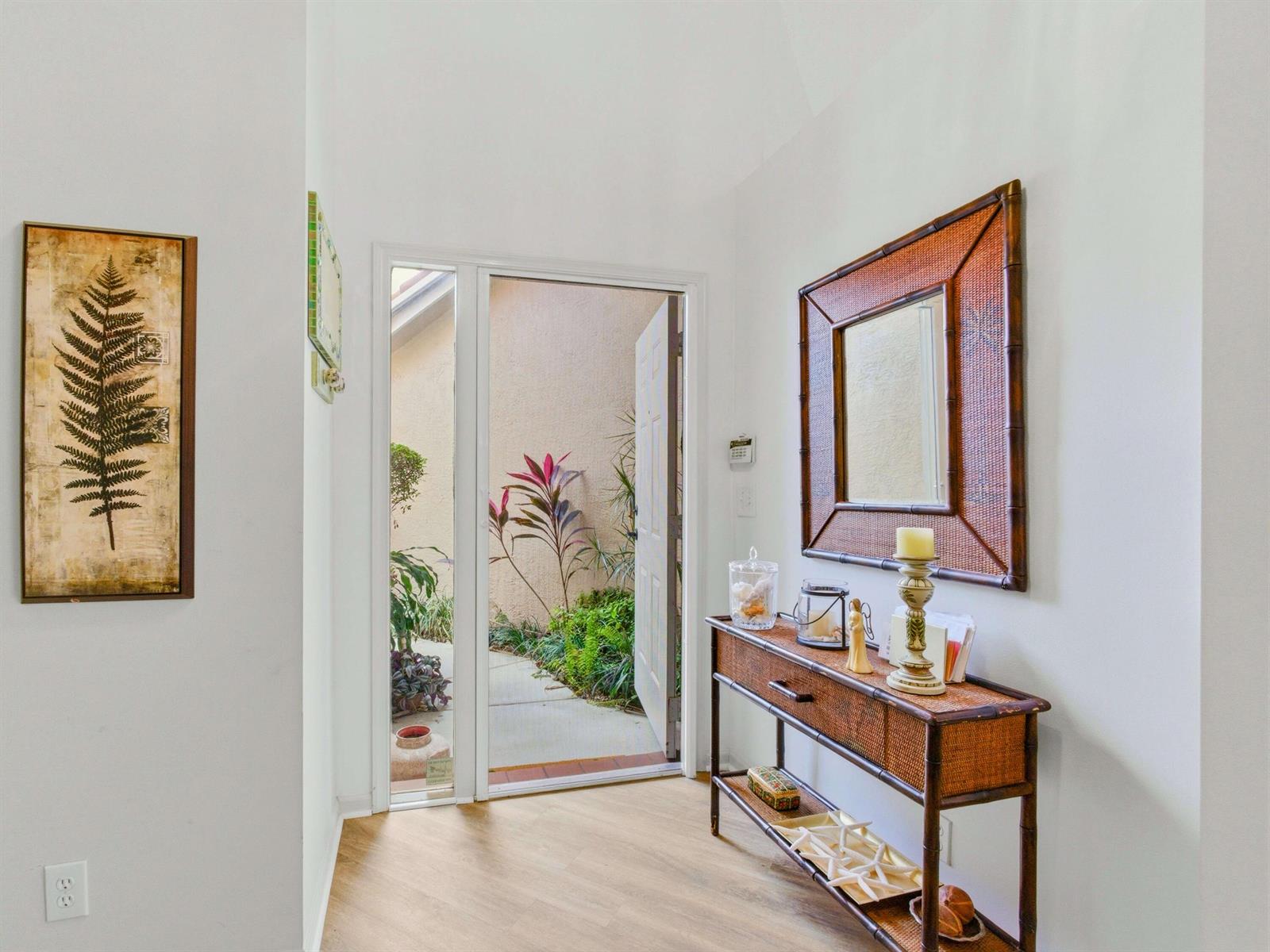 An entryway features a console table, a mirror, wall art, and an open front door — 6367 Long Key Lane, Boynton Beach FL 33472, BOYNTON BEACH, FL