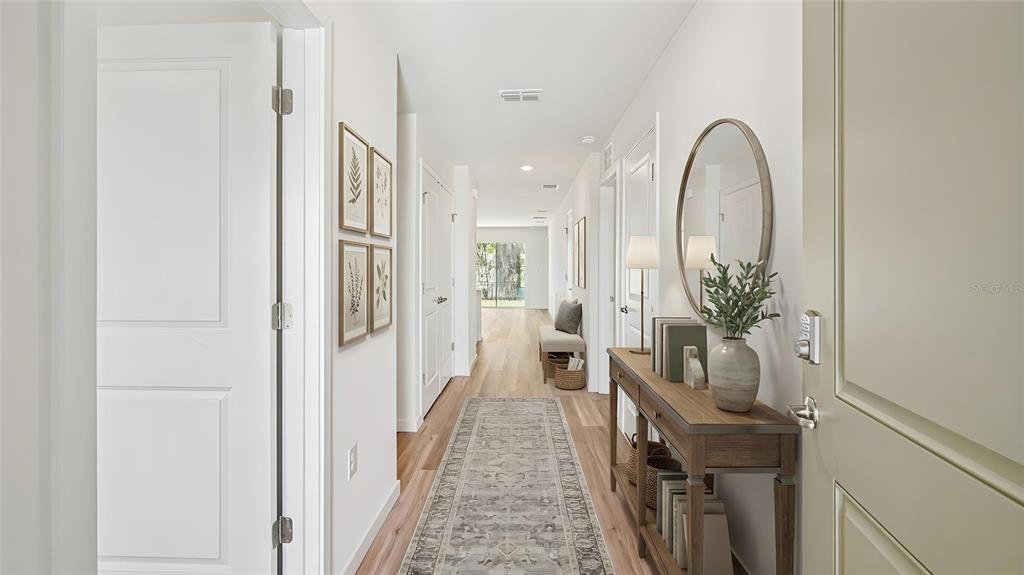 A bright hallway features light wood flooring, a long runner rug, and a console table — 7812 SW 46TH COURT, OCALA, FL