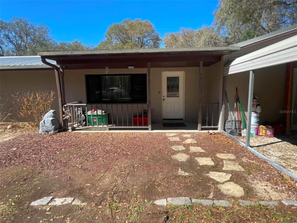 A covered front porch with a railing leads to a white door on a house — 17530 SE HIGHWAY 452, UMATILLA, FL