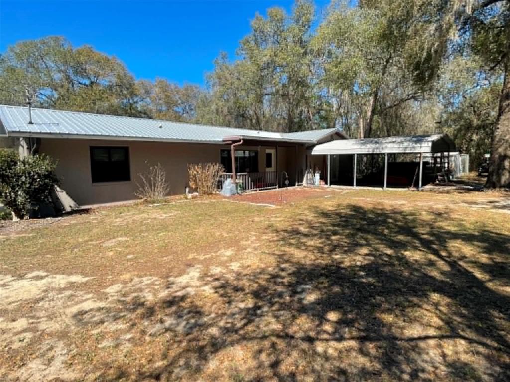 A single-story house with a metal roof, a covered porch, and an attached carport — 17530 SE HIGHWAY 452, UMATILLA, FL