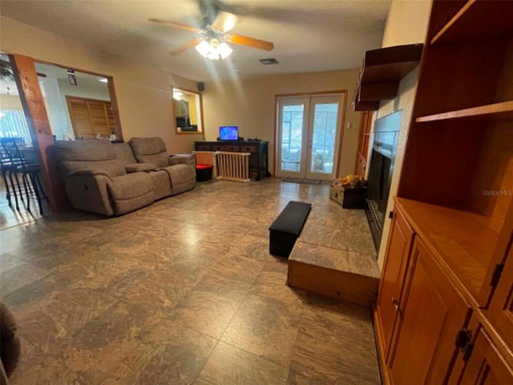 A living room features tile flooring, a fireplace, a ceiling fan, and a brown sofa — 17530 SE HIGHWAY 452, UMATILLA, FL