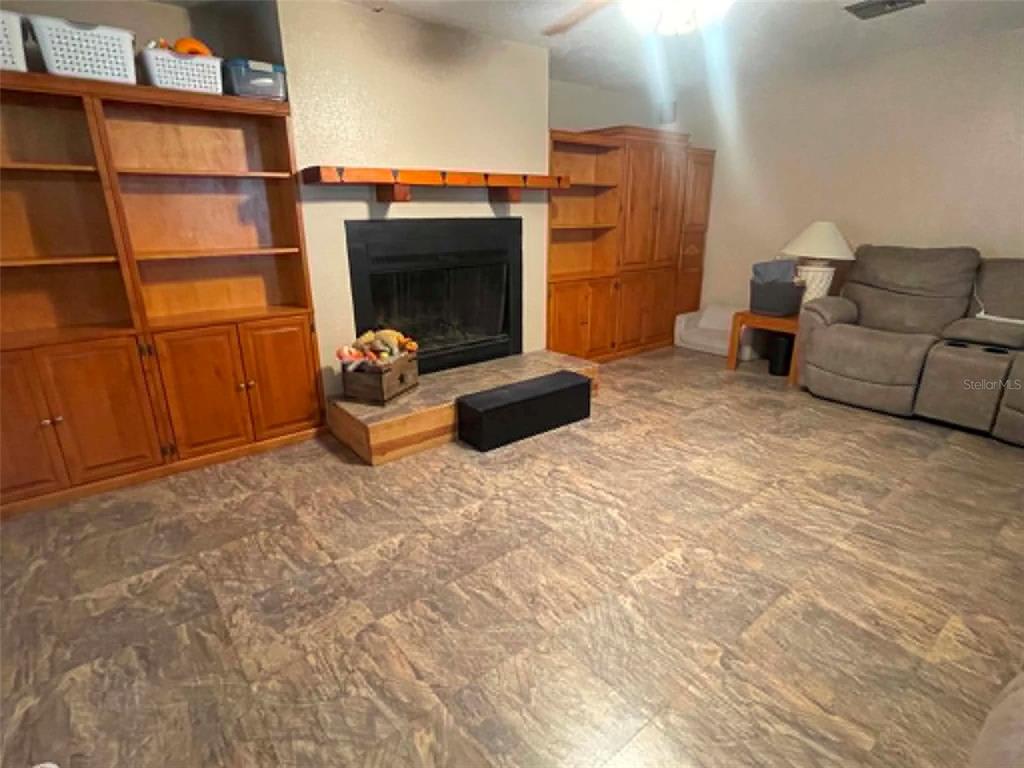 A living room features a fireplace, built-in wooden shelving, and tile flooring — 17530 SE HIGHWAY 452, UMATILLA, FL