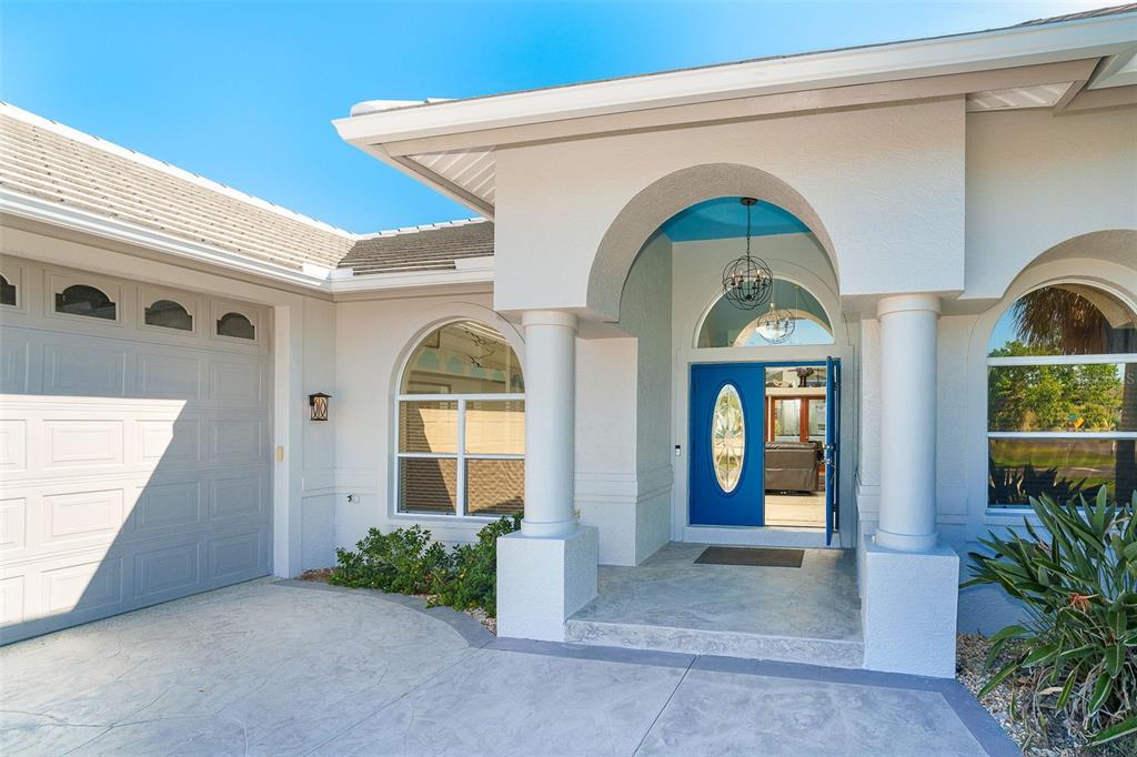 The exterior of a house features a blue front door, arched windows, and columns — 100 N GREEN DOLPHIN DRIVE, CAPE HAZE, FL