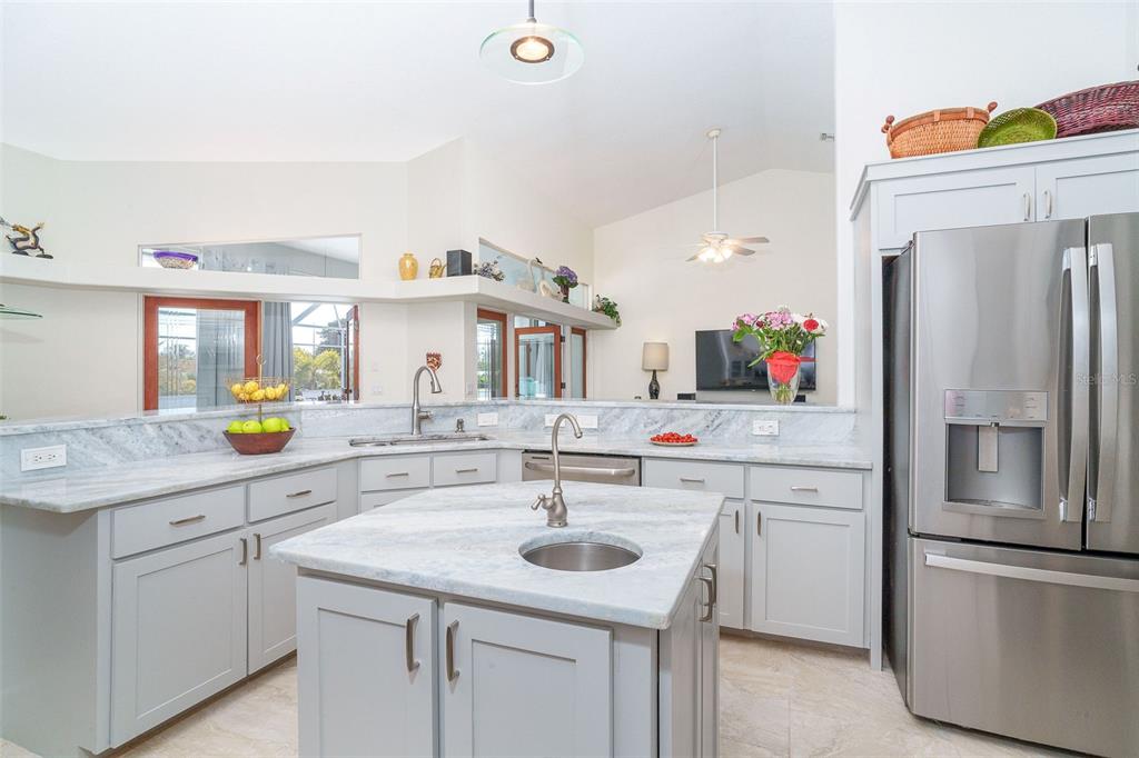 A kitchen with light gray cabinets, marble countertops, a center island, and stainless steel appliances — 100 N GREEN DOLPHIN DRIVE, CAPE HAZE, FL