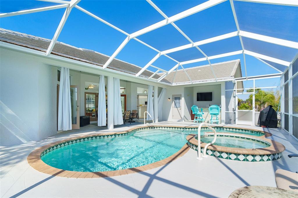 A screened-in patio features a swimming pool, a raised hot tub, and outdoor seating — 100 N GREEN DOLPHIN DRIVE, CAPE HAZE, FL