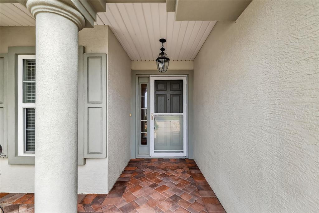 A covered entryway features a brick-paver floor, a white column, and a dark front door — 11217 SE 170TH LANE, SUMMERFIELD, FL