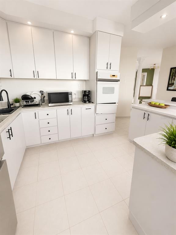 A bright kitchen features white cabinetry, light tile flooring, and a built-in wall oven — 843 CAM LOS RAMOS, TRUJILLO ALTO, PR