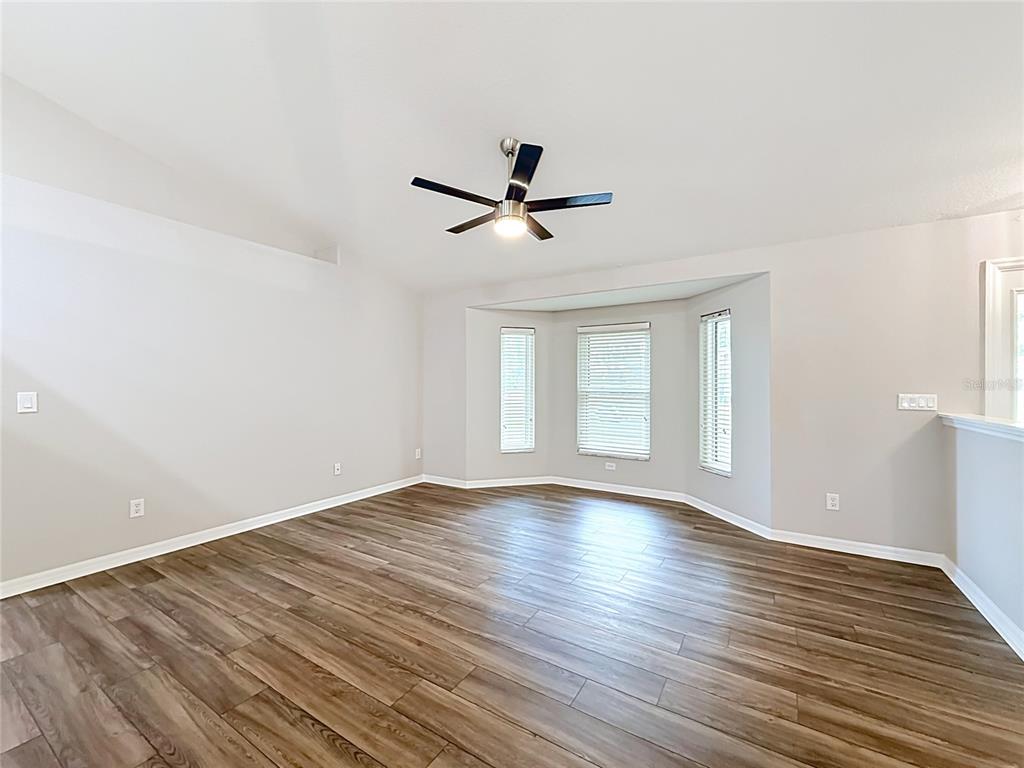 An empty room with light gray walls, wood-look flooring, and a bay window — 9537 SW 53RD CIRCLE, OCALA, FL