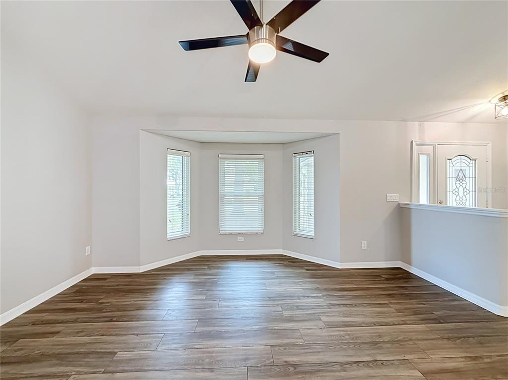 An empty room with wood-look flooring, a ceiling fan, and a bay window — 9537 SW 53RD CIRCLE, OCALA, FL