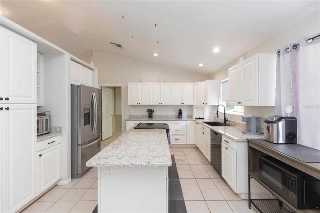 A kitchen with white cabinets, granite countertops, a central island, and stainless steel appliances — 34299 BELT DRIVE, DADE CITY, FL