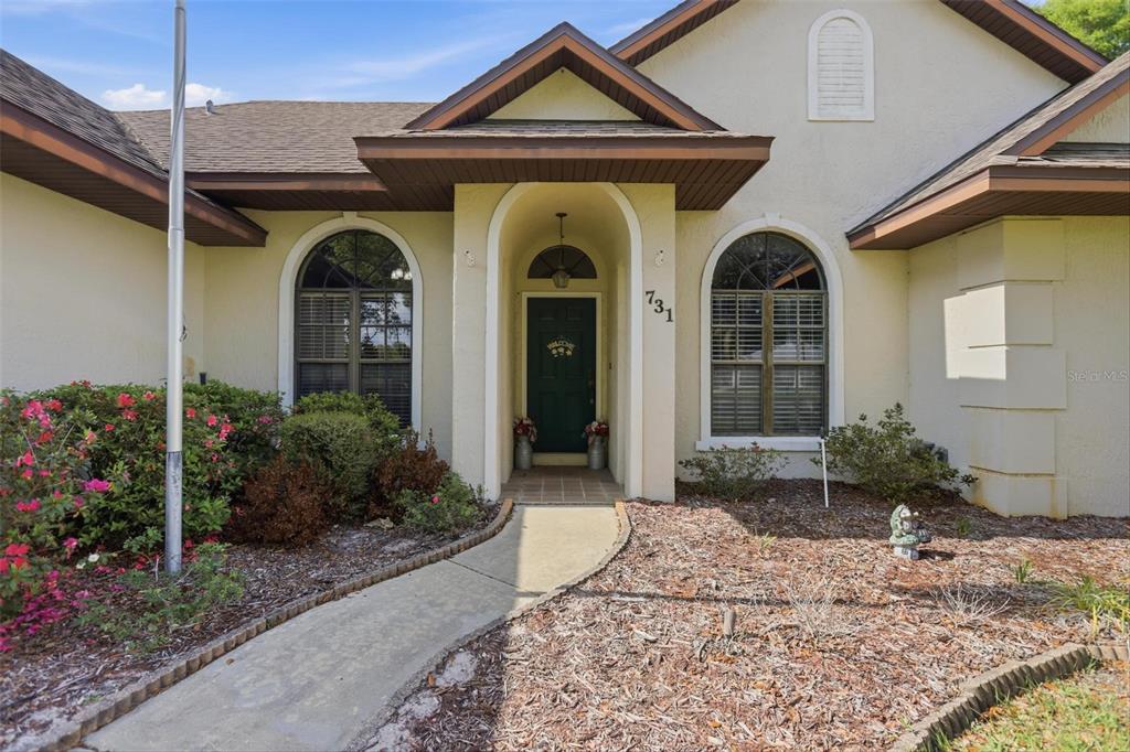 A front exterior view of a house with a walkway leading to a covered entrance — 731 EDGEWILD COURT, ORANGE CITY, FL