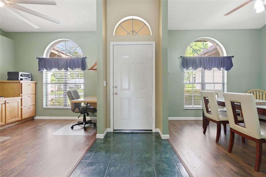 An entryway with a white door, tile floor, and flanking rooms with wood-look flooring — 731 EDGEWILD COURT, ORANGE CITY, FL