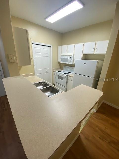 A kitchen with white appliances, light-colored cabinets, and a peninsula countertop — 2010 E PALM AVENUE UNIT 15208, TAMPA, FL