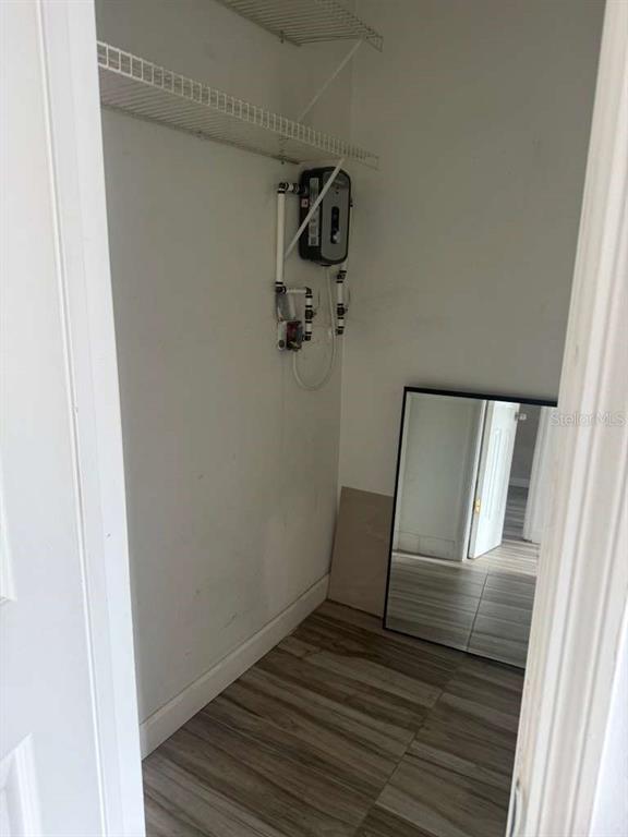 A small utility closet features wood-look flooring, wire shelving, and a wall-mounted tankless water heater — 807 WELDONA LANE UNIT 106, ORLANDO, FL