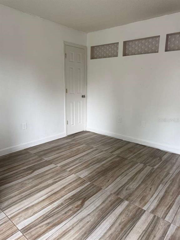 A room with white walls, a closed door, and wood-look tile flooring — 807 WELDONA LANE UNIT 106, ORLANDO, FL