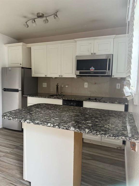 A kitchen features white cabinets, granite countertops, a stainless steel refrigerator, and a breakfast bar — 807 WELDONA LANE UNIT 106, ORLANDO, FL