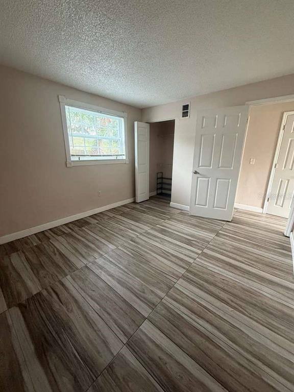 A bedroom features light-colored walls, wood-look tile flooring, a window, and two white doors — 807 WELDONA LANE UNIT 106, ORLANDO, FL