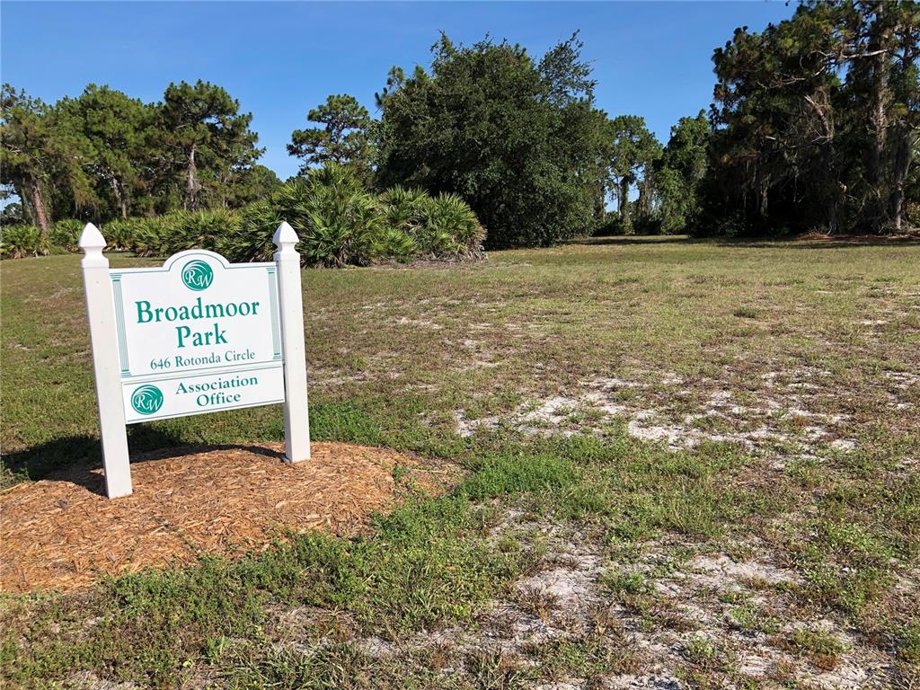 A sign for Broadmoor Park stands in a grassy, wooded lot under a clear sky — 1153 BOUNDARY BOULEVARD, ROTONDA WEST, FL