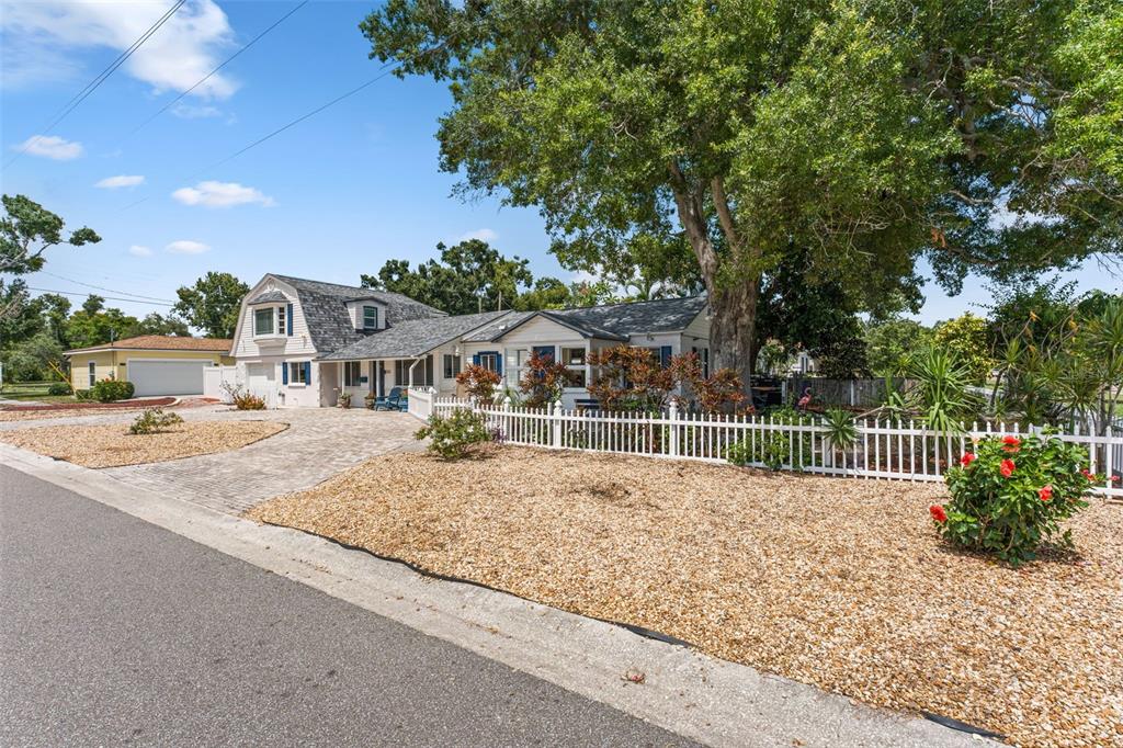 A white house with a gambrel roof sits behind a white picket fence and driveway — 601 45TH STREET N, ST PETERSBURG, FL