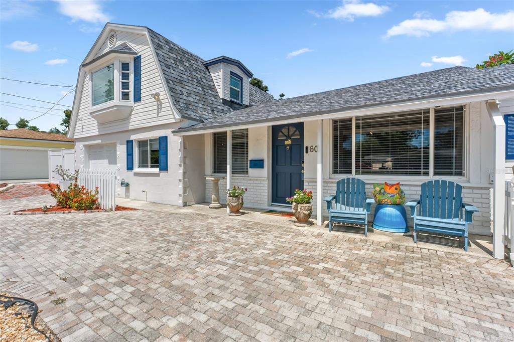 The exterior of a white house features a gambrel roof, blue shutters, and a brick driveway — 601 45TH STREET N, ST PETERSBURG, FL