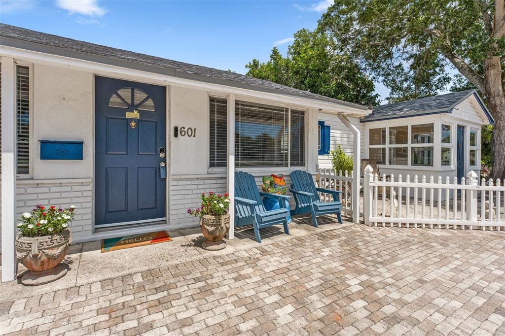 A white house with a blue door, brick patio, and two blue Adirondack chairs — 601 45TH STREET N, ST PETERSBURG, FL