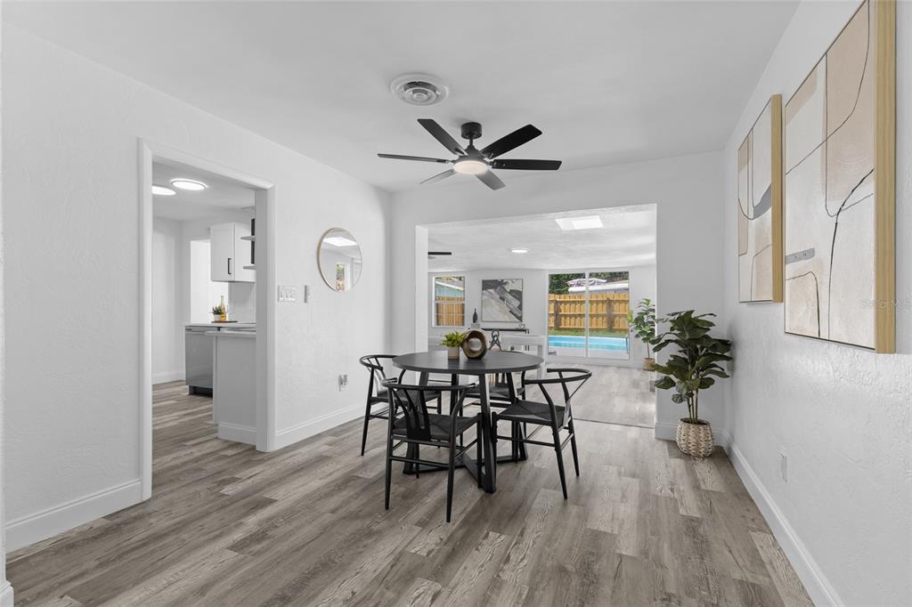 A dining area with a round table, black chairs, and wood-look flooring leads to a patio — 1259 SCOTTSDALE DRIVE, ORMOND BEACH, FL